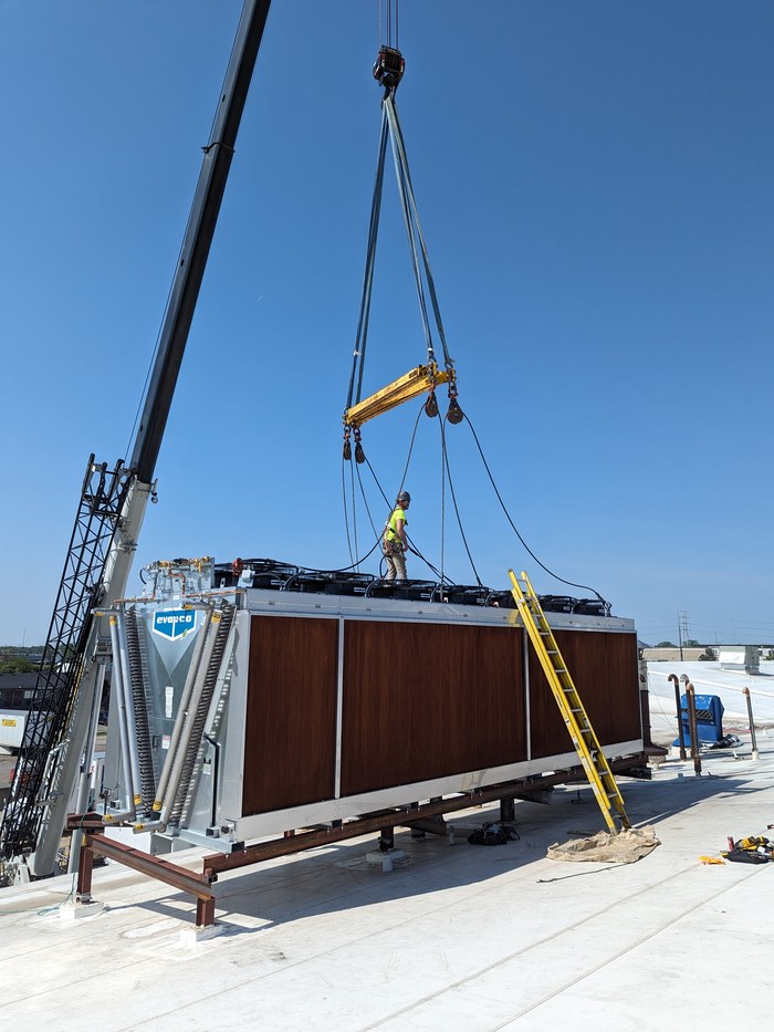 Crew using a crane to rig an Evapco cooling unit onto a rooftop