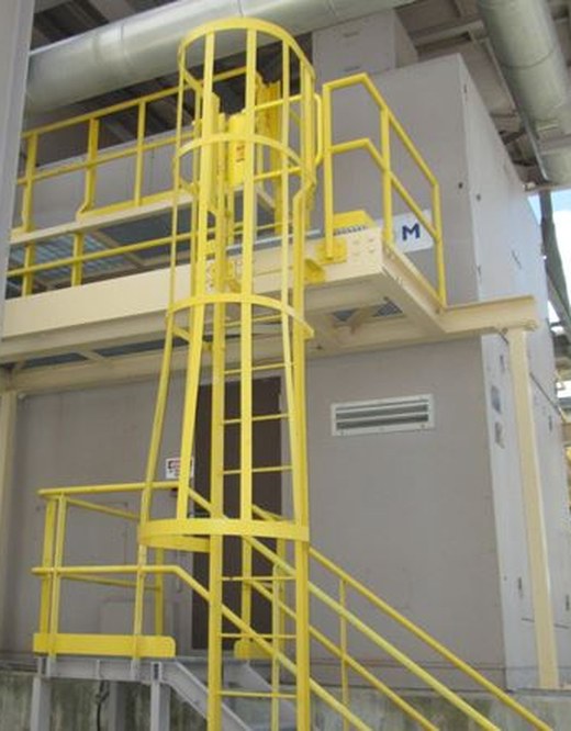 Yellow caged ladder, guardrails, and access platform installed on elevated plant equipment