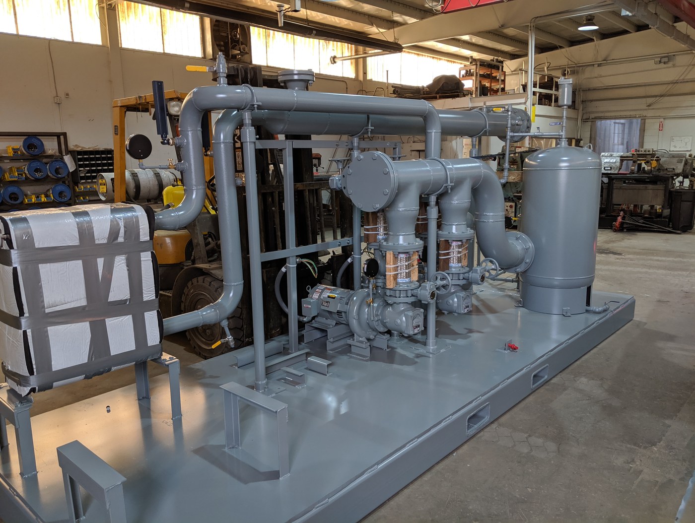 Completed grey process equipment skid with piping, pumps, and tank fabricated in Pyramid's shop