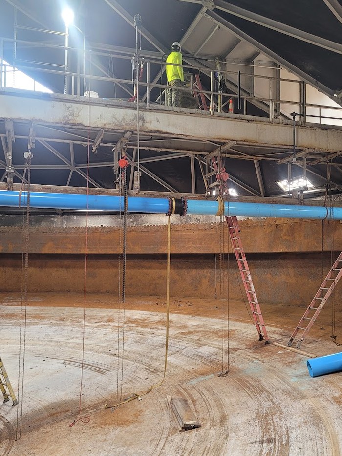 Crew installing blue piping inside a water storage tank during a retrofit